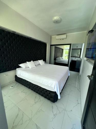 1 dormitorio con 1 cama grande con sábanas blancas en EL Encanto de tu Selva, en Tarapoto