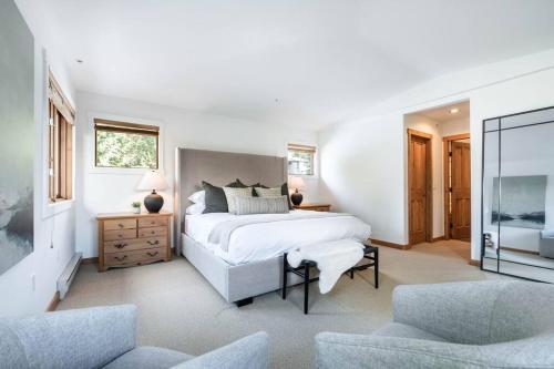 ein weißes Schlafzimmer mit einem großen Bett und 2 Stühlen in der Unterkunft Taluswood Ridge by Outpost Whistler in Whistler