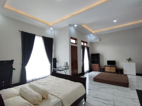 a bedroom with a large white bed and windows at Saira Hotel dan Homestay Syariah in Sleman