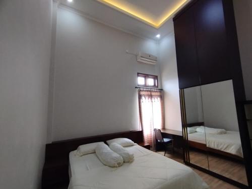 a bedroom with a bed and a mirror and a window at Saira Hotel dan Homestay Syariah in Sleman