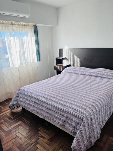a bedroom with a bed with a striped blanket on it at Apartamento Pacifico Delta Suites in Bahía Blanca