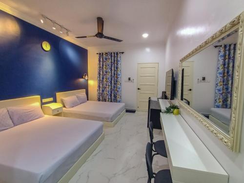 a hotel room with two beds and a mirror at Villa Bonda Langkawi in Pantai Cenang