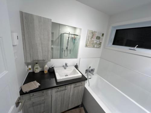 a bathroom with a sink and a mirror and a tub at Unactivated in Longueuil