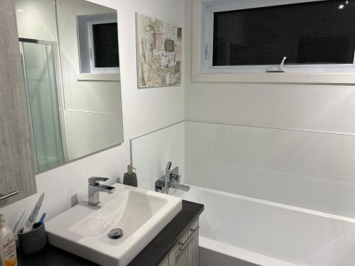 Baño blanco con lavabo y espejo en Unactivated en Longueuil