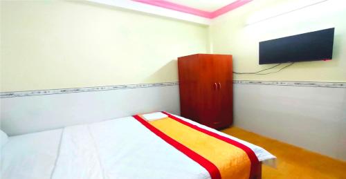 een slaapkamer met een bed en een flatscreen-tv bij Hoàng Xuân 797 Hà Huy Giáp in Ho Chi Minh-stad
