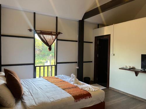 a bedroom with a bed and a large window at Villa Namkhan Heritage in Luang Prabang