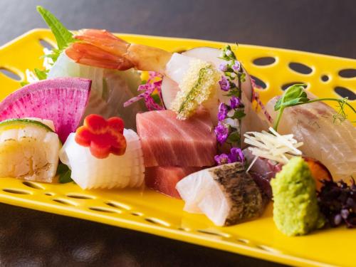 a yellow plate with sushi and vegetables on it at Ryuguden in Hakone