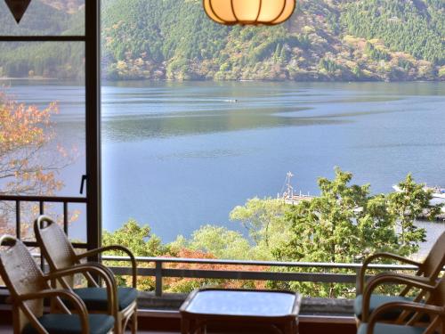 a room with chairs and a view of a lake at Ryuguden in Hakone