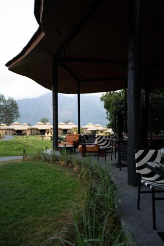 a patio with chairs and tables and umbrellas at Toteme Glamping and Hot Spring Kintamani in Kintamani