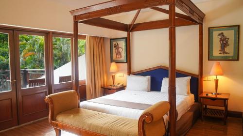 a bedroom with a canopy bed and a chair at Lorin Solo Hotel in Solo