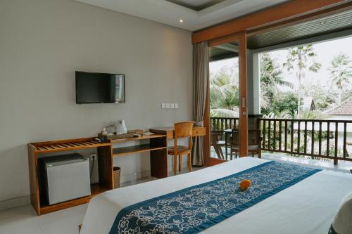 sypialnia z łóżkiem i biurkiem oraz balkon w obiekcie The Umari w mieście Ubud
