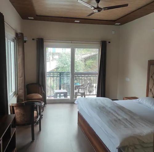 a bedroom with a bed and a balcony with a view at Whyt Bank Cottage Comfort Stays in Mussoorie