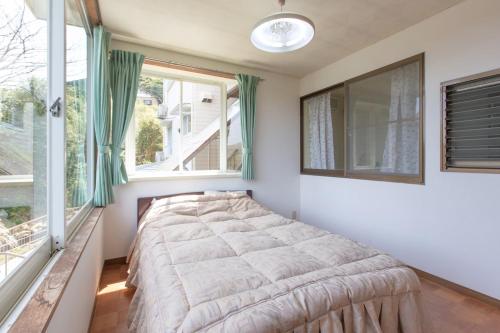 a bedroom with a bed and two windows at 森の風 in Higashiizu