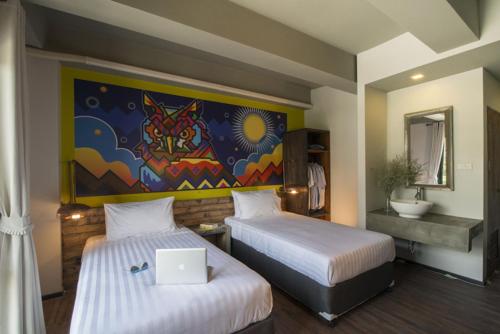 a room with two beds with a laptop on top of it at Cacha Hotel Bangkok - Near BTS Ratchathewi & Siam in Bangkok