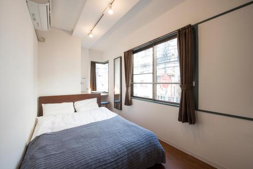 a bedroom with a bed and a window at KandO Hostel Ueno in Tokyo