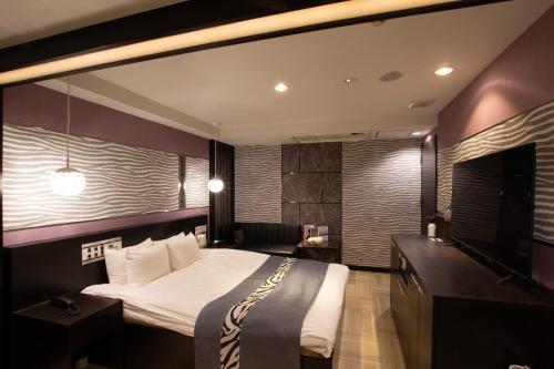 ein Schlafzimmer mit einem großen Bett und einem TV in der Unterkunft HOTEL KSEA (Adult Only) in Matsudo