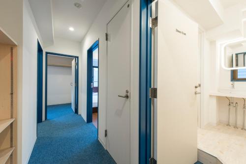 a hallway with blue carpet and white walls and blue flooring at KandO Hostel Ueno in Tokyo