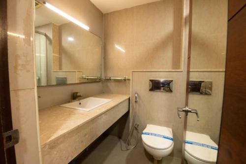 a bathroom with a sink and a toilet and a mirror at Hotel High Point in Tiruchirappalli