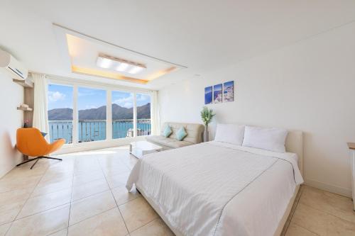 a bedroom with a bed and a couch and a window at Melodia Pension in Geoje 