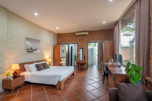 um quarto com uma cama, uma secretária e uma televisão em Mekong Long Thanh Resort & Reststop em Ấp Thanh Nguyên