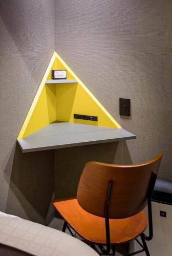 a yellow and white shelf with a chair in a room at Sai Hotel in Shizuoka