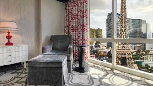 um quarto com uma cadeira e uma janela com a torre Eiffel em Paris Las Vegas Resort & Casino em Las Vegas