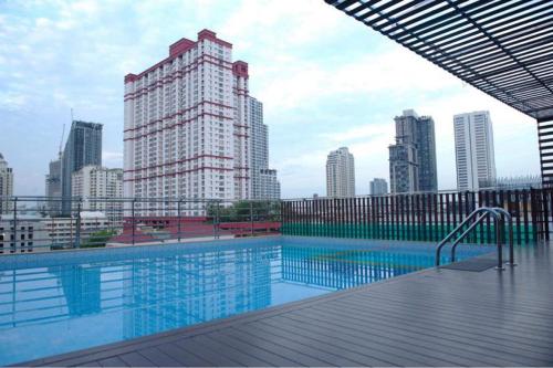 a large swimming pool in a city with tall buildings at Top High Airport Link Hotel, Bangkok in Bangkok