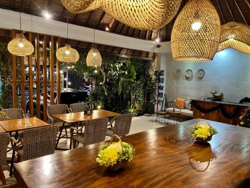 ein Restaurant mit Tischen, Stühlen und Hängelampen in der Unterkunft Villa Puriartha Ubud - CHSE Certified in Ubud