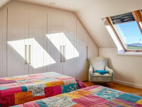 Schlafzimmer im Dachgeschoss mit einem Bett und einem Stuhl in der Unterkunft The Longhouse At Threave in Castle Douglas