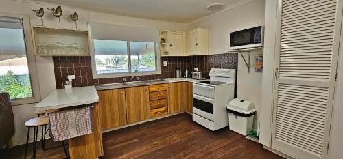 una cocina con electrodomésticos blancos y armarios de madera en Patrick Crescent 18 - Kalbarri WA, en Kalbarri