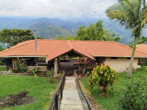 une maison avec un toit orange et un palmier dans l'établissement Cabaña Bella Vista, à Pereira