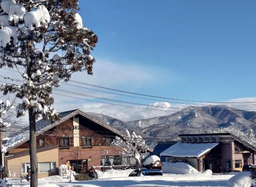 a house covered in snow with mountains in the background at Hotel Tae Windsor in Myoko
