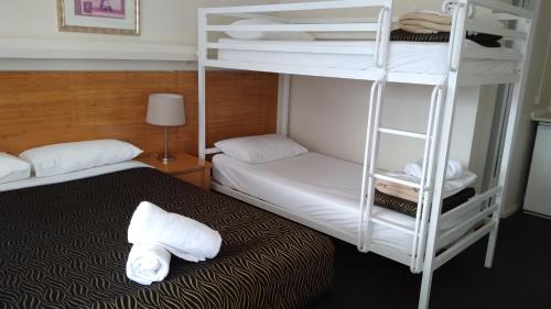 a room with two bunk beds and a bed with towels at City Park Motel and Apartments in Wagga Wagga