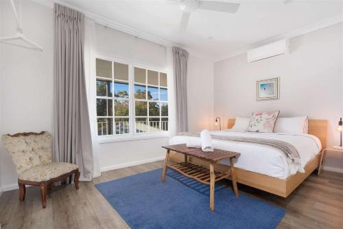 a bedroom with a bed and a table and a chair at Myrtle Tree Lodge Leaves, Kangaroo Valley in Kangaroo Valley