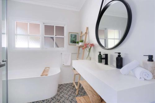 uma casa de banho com um lavatório branco e um espelho. em Myrtle Tree Lodge Leaves, Kangaroo Valley em Kangaroo Valley