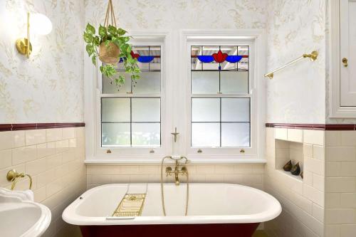 a bath tub in a bathroom with two windows at Lemon Tree Cottage, Kangaroo Valley in Kangaroo Valley
