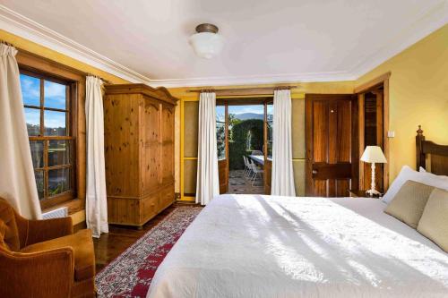 1 dormitorio con 1 cama blanca grande y ventanas en Kayenta, Kangaroo Valley, en Valle Kangaroo