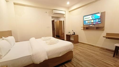ein Hotelzimmer mit einem Bett und einem Flachbild-TV in der Unterkunft Hotel Tapovanam Rishikesh in Rishikesh