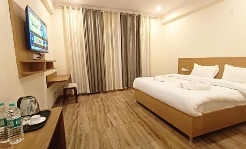 ein Hotelzimmer mit einem Bett und einem Flachbild-TV in der Unterkunft Hotel Tapovanam Rishikesh in Rishikesh