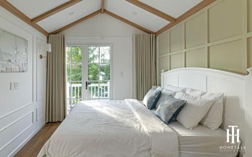 1 dormitorio con 1 cama blanca grande con almohadas azules en Villa 3PN Novaworld Phan Thiết, en Phan Thiet