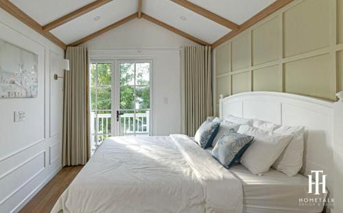 a bedroom with a large white bed with blue pillows at Villa 3PN Novaworld Phan Thiết in Phan Thiet