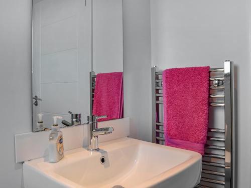 ein Badezimmer mit einem weißen Waschbecken und rosa Handtüchern in der Unterkunft The Longhouse At Threave in Castle Douglas