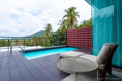 - un balcon avec une piscine, une table et des chaises dans l'établissement Matina Mountain Resort, à Koh Tao