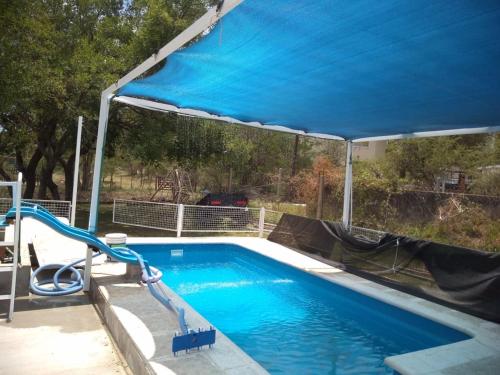 a swimming pool with a blue canopy over it at Los aromitos in La Bolsa