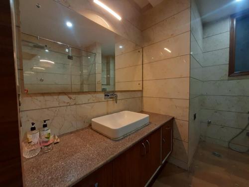 een badkamer met een wastafel en een glazen douche bij Nearmi Hotels Banquets Medanta IKEA Sector 47 - Gurugram in Gurgaon