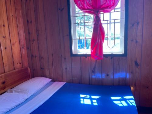a bedroom with a bed and a window with a red curtain at Saint Joseph Inn in Sagada