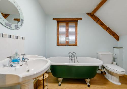 a bathroom with a green tub and a toilet at Chestnut Cottage in Manorbier