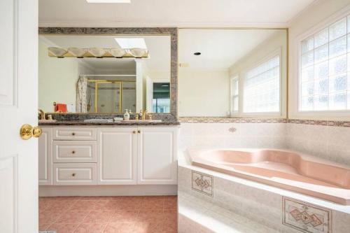 a bathroom with a pink tub and a mirror at Master Bedroom with Two Queen Sized Bed in Richmond