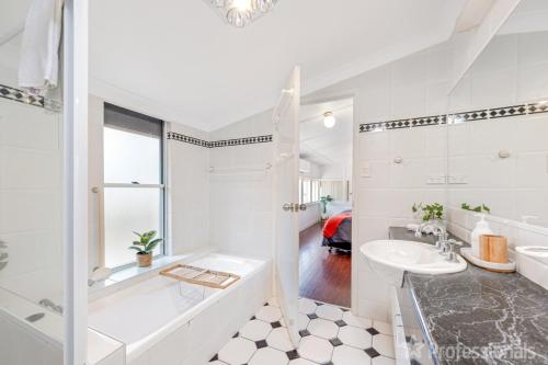 Un baño blanco con bañera y lavabo. en Beachfront Holiday Cottage, en Zilzie
