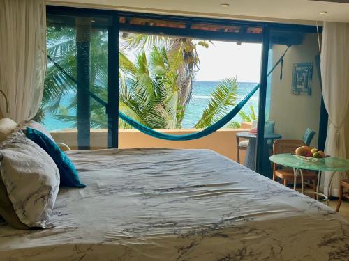 1 dormitorio con 1 cama y vistas al océano en Beachfront Hammock Heaven en Akumal